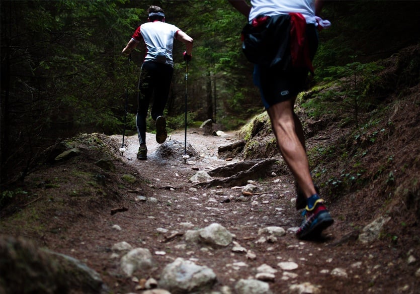deux hommes qui font du fast hiking sur un sentier en forêt